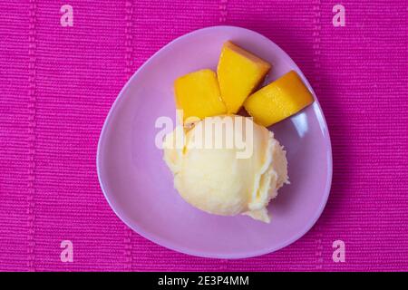 Une cuillère maison de sorbet à la mangue avec des morceaux de mangue frais de ci-dessus Banque D'Images