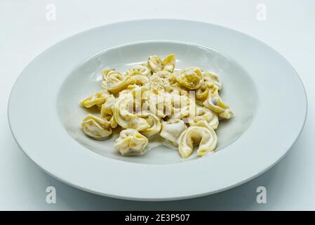 Tortellini alla panna avec du fromage Parmigiano Reggiano dans un plat blanc. Pâtes italiennes traditionnelles. Banque D'Images