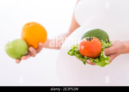 Femme enceinte tenant des légumes et des fruits biologiques dans ses mains Banque D'Images