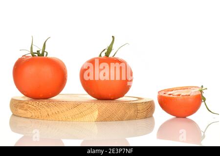 Deux tomates vertes entières et une demi-tomates vertes mûres biologiques juteuses, sur un support rond en bois, sur fond blanc. Banque D'Images