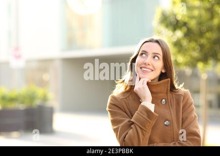 Portrait d'une femme heureuse en hiver dans la rue penser à regarder de côté avec l'espace de copie Banque D'Images