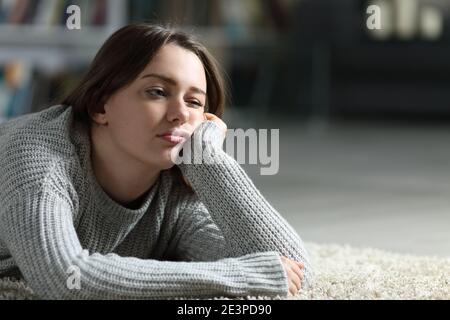 Un adolescent ennuyé qui regarde loin, allongé sur le sol à la maison Banque D'Images