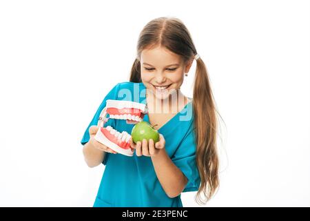 Enfant avec un sourire crasseux, tenant un modèle anatomique de mâchoire et de pomme dans ses mains. Concept de l'effet de la nourriture sur les dents des enfants Banque D'Images