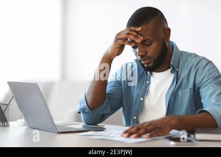 Problèmes de travail. Un homme d'affaires afro-américain frustré lisant des documents au bureau Banque D'Images