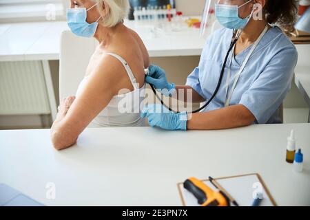 Médecin utilisant un stéthoscope sur un adulte âgé Banque D'Images