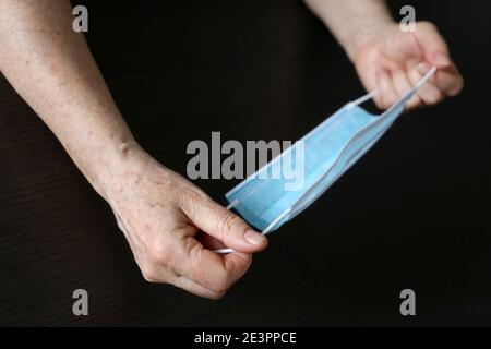 Femme âgée avec un masque médical dans les mains froissées. Protection contre les coronavirus pour les personnes âgées Banque D'Images