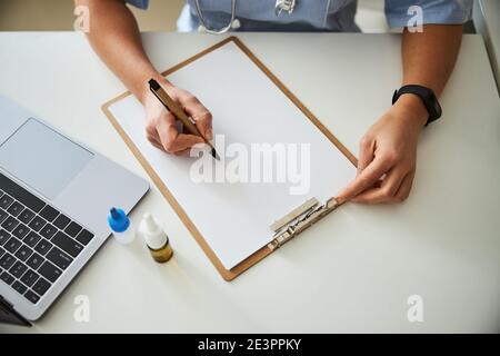 Mains avec un stylo au-dessus d'un papier d'ordinateur portable Banque D'Images