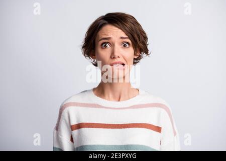 Portrait en gros plan d'une jolie fille aux cheveux bruns et effrayée qui attend des nouvelles lèvre de morsure isolée sur fond gris pastel Banque D'Images