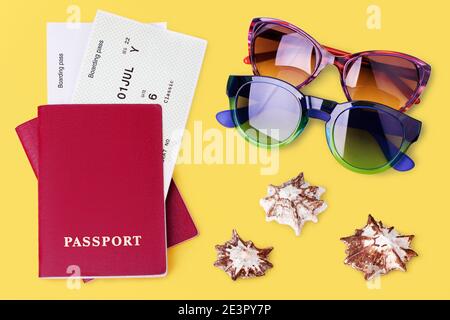 Passeport rouge, carte d'embarquement, lunettes de soleil, mouillage de fond jaune, billet d'avion, coque de mer, voyage en avion, vacances d'été ensoleillées à la plage Banque D'Images