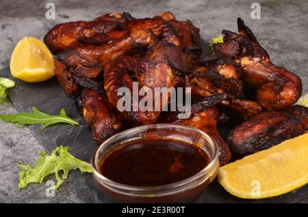 Ailes de poulet grillées sur une assiette de citron et de sauce. Rôti dans des ailes de poulet au miel croustillantes et croustillantes Banque D'Images