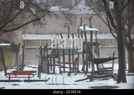 Aire de jeux déserte enneigée pour enfants avec toboggans et tours d'escalade entouré de bâtiments en pierre et de murs dans la vieille ville De Ratisbonne en wi Banque D'Images