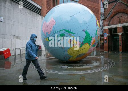 LONDRES, Royaume-Uni 20 janvier 2021. Les piétons se promène devant la sculpture du globe conçue par Mark Wallinger « The World retourné » devant la London School of Economics. Jusqu'à présent, plus de 4 millions de personnes ont reçu la première dose du vaccin COVID-19 au Royaume-Uni dans le cadre d'un programme d'inoculation avec l'ouverture de 10 nouveaux centres de vaccination de masse. Credit: amer ghazzal / Alamy Live News Banque D'Images