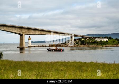 Pont de Skye, phare et gardiens cottages sur Eilean Bàn, avec bateau de pêche passant Banque D'Images