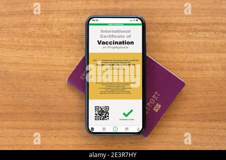 Un smartphone avec une illustration numérique d'un exemple de certificat de vaccination contre la maladie de Covid-19 est organisé sur un passeport. Banque D'Images