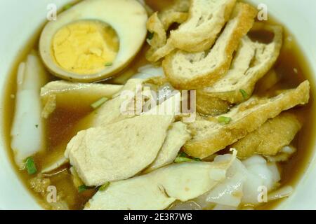 Pâte de farine de riz chinoise avec tranche de poulet et tofu frit garniture d'œuf dans la soupe brune Banque D'Images