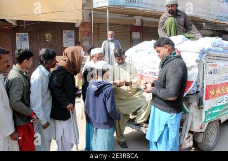 Un grand nombre de personnes se rassemblent pour acheter des sacs de farine sur le prix des subventions dans un magasin de services publics mobiles vendu par le gouvernement de Sindh, dans la région de Latifabad à Hyderabad le mercredi 20 janvier 2021. Banque D'Images