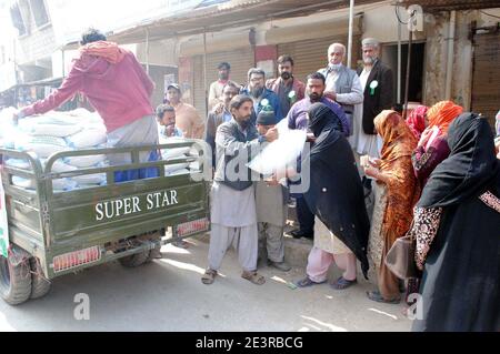 Un grand nombre de personnes se rassemblent pour acheter des sacs de farine sur le prix des subventions dans un magasin de services publics mobiles vendu par le gouvernement de Sindh, dans la région de Latifabad à Hyderabad le mercredi 20 janvier 2021. Banque D'Images