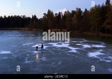 Mère et fils avec un phare sur un lac gelé au crépuscule Banque D'Images