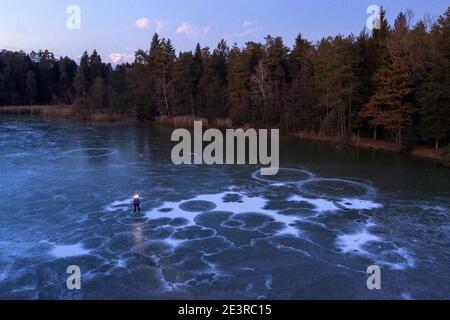 Femme avec un phare debout sur un lac gelé au crépuscule Banque D'Images