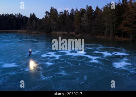 Femme avec un phare debout sur un lac gelé au crépuscule Banque D'Images