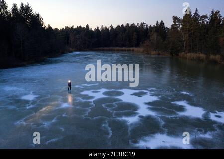 Femme avec un phare debout sur un lac gelé au crépuscule Banque D'Images