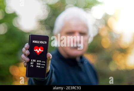 Personne âgée montrant une application de santé mobile sur le smartphone, qui indique la tension artérielle. Banque D'Images