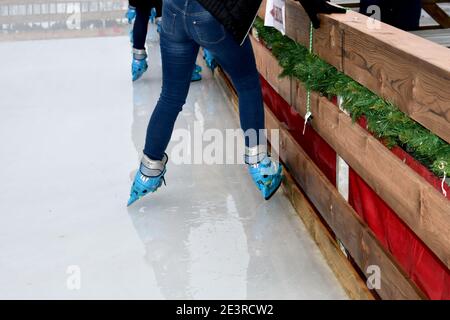 gros plan de la famille des pieds de patineurs de glace se préparant à aller sur la patinoire extérieure, portant des patins de glace bleus, en hiver Banque D'Images