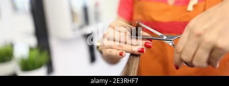 Femme coiffeur tient les cheveux et les moulins leurs extrémités Banque D'Images