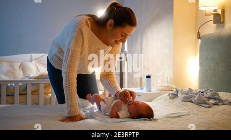 Une jeune mère qui s'occupe donne de la sucette à son petit garçon qui pleure au lit la nuit. Un parent donne une sucette au nouveau-né. Concept d'aimer et Banque D'Images