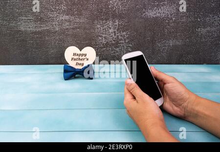 Smartphone entre les mains d'une femme, carte de vœux Happy Pères Day ou affiche avec accessoires pour hommes. Banque D'Images
