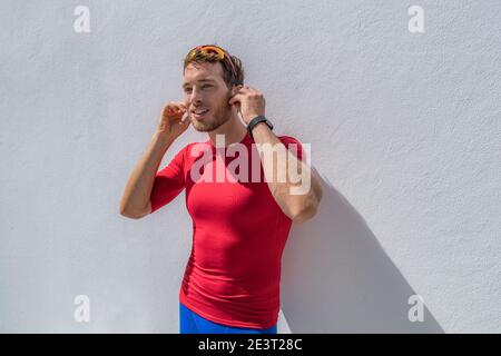 Athlète coureur homme se prépare à l'entraînement avec des écouteurs Bluetooth sans fil pour écouter de la musique sur smartphone pendant l'exercice de course. Banque D'Images