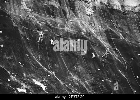 Les travailleurs renforcent la pente de la montagne avec un maillage métallique empêchant la chute sur la route. Hondarribia, Espagne. Résumé du concept de sécurité Banque D'Images