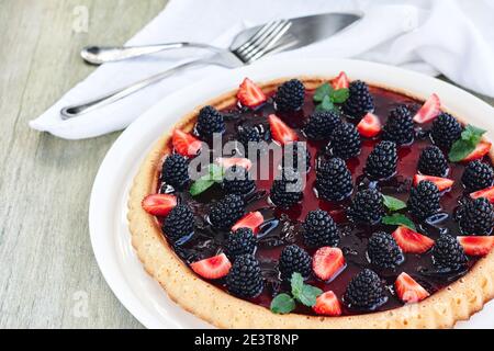 Tarte aux baies d'été avec mûres et fraises sur une table en bois. Banque D'Images