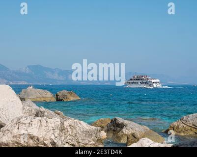 Cala Goloritze, Sardaigne, Italie, 8 septembre 2020: Une vue de bateau de croisière touristique à l'eau turquoise du golfe d'Orosei vu de la côte rocheuse Banque D'Images