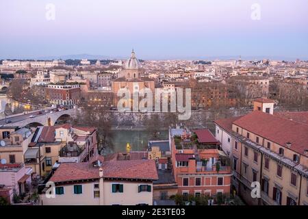 Vue sur les toits de Trastevere à travers la rivière Tibre jusqu'au centre de Rome, Italie, au coucher du soleil. Église de San Giovanni Battista dei Fiorentini dans le FO Banque D'Images