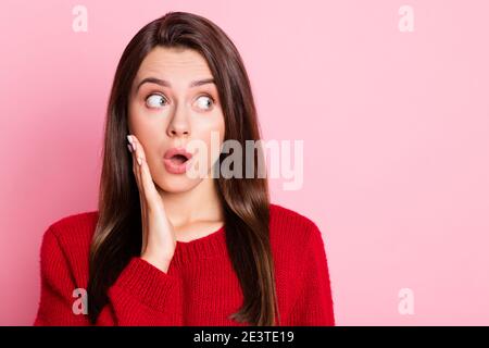 Photo portrait d'une fille surprise étonnée regardant à côté avec ouverture de la bouche touchant le visage portant des vêtements rouges décontractés isolés dessus couleur rose Banque D'Images