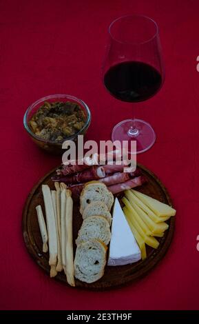 Verre de vin accompagné de salami, de fromage, de mortadelle, de jambon cru sur une planche de bois et d'aubergine marinée Banque D'Images