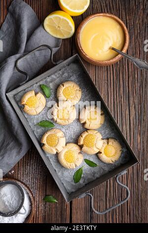 Délicieux en-cas sucré, biscuits au citron crud avec empreinte de pouce arrosé de sucre en poudre sur fond de bois rustique Banque D'Images