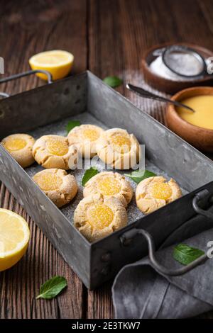 Délicieux en-cas sucré, biscuits au citron crud avec empreinte de pouce arrosé de sucre en poudre sur fond de bois rustique Banque D'Images