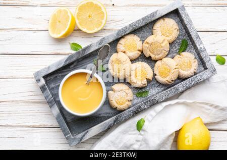 Délicieux en-cas sucré, biscuits au citron crud avec empreinte de pouce arrosé de sucre en poudre sur fond de bois rustique Banque D'Images