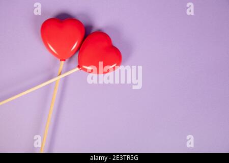 les coeurs sur un bâton se trouvent sur un fond violet, ils se croissent l'un l'autre Banque D'Images