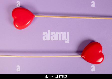 les coeurs sur un bâton se trouvent sur un fond violet, vue de dessus Banque D'Images