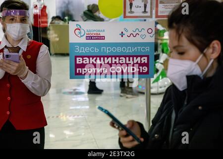 Moscou, Russie. 20 janvier 2021 UN membre du personnel dans un masque facial est vu à l'entrée d'un bureau de services gouvernementaux My documents dans le centre commercial d'Afimall City où un site temporaire de vaccination COVID-19 a été ouvert. La Russie a commencé la vaccination de masse contre une nouvelle infection à coronavirus COVID-19 avec le vaccin Spoutnik V. La bannière indique « la vaccination par le COVID-19 est effectuée ici » Banque D'Images