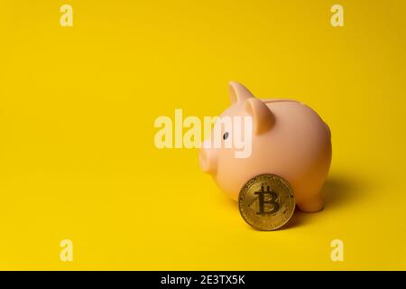 Cochon rose comme caisse d'argent sur fond jaune avec BTC pièce Banque D'Images