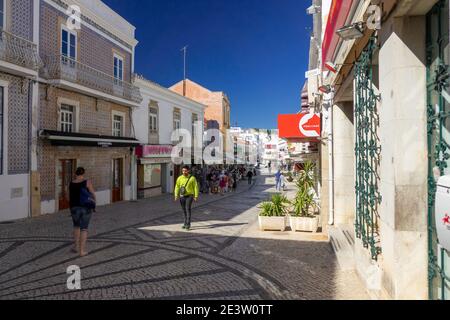 Les touristes marchent sur la Rua 5 de Outubro Albufeira vieille ville pendant l'hiver en février, les bâtiments en façade et Cobblestone Street Albufiera Portugal Banque D'Images