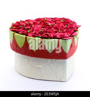 Photo d'un papier en forme de coeur et carte cadeau de la Saint-Valentin boîte de chocolats avec roses en papier rouge et feuilles vertes avec une base blanche Banque D'Images