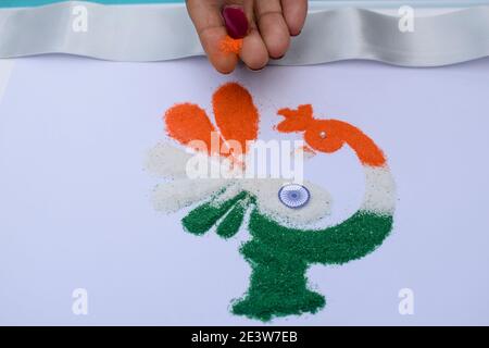 Femme faisant des rangoli design tricolore safran blanc et Vert à l'occasion de la célébration de la veille de la république indienne Banque D'Images