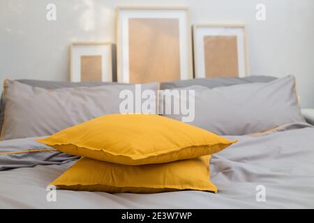 Chambre, lit et oreillers jaune lumineux sur le lit gris ultime. Couleurs tendance 2021 Design intérieur Banque D'Images