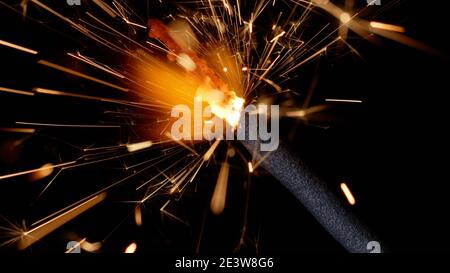 Gros plan macro de flamant flambeau bougie du feu bengale devant un fond noir foncé. Des lumières étincelantes pour les fêtes d'anniversaire, les mariages, le nouvel an, la veille de Noël, les fêtes de Noël Banque D'Images
