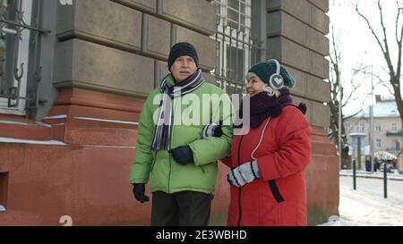 Personnes âgées adultes touristes marchant dans la vieille ville en hiver parlant et faisant des gestations en appréciant la conversation, en s'amusant. Famille senior et communication vacances concept de vacances Banque D'Images